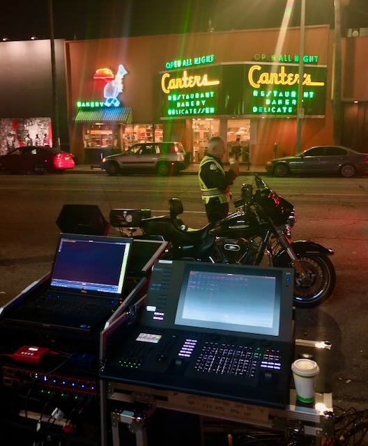 On-location lighting console set up across the street from Canter's neon-lit storefront at night.