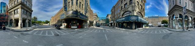 Wide panoramic plate of a European-style street corner, location scout reference for an exterior build.