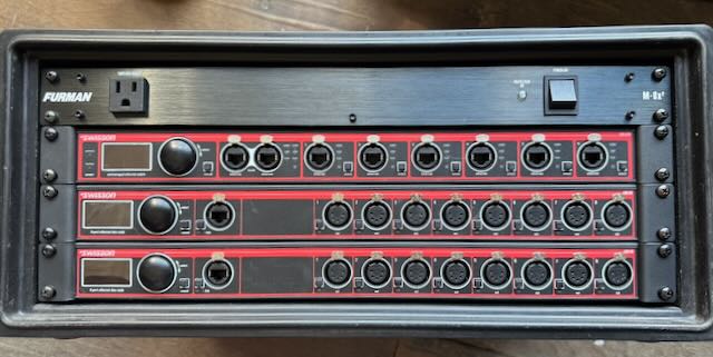 Furman-fed power and data distro rack stocked with red-faced network switches, ready for tour.
