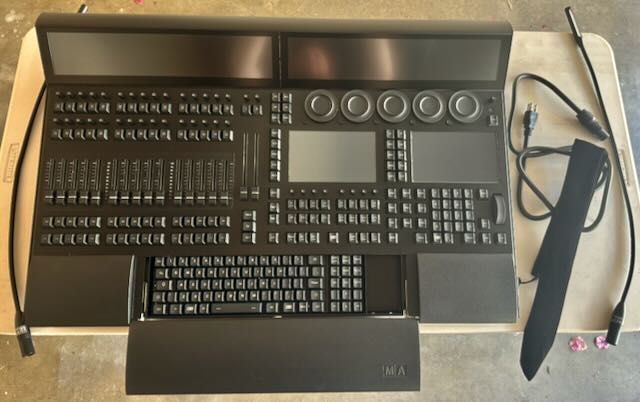 grandMA lighting console on a roadcase, faders and encoders ready for programming.